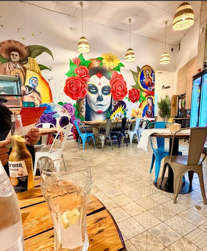 Interior de La Bigotuda con mural y mesas